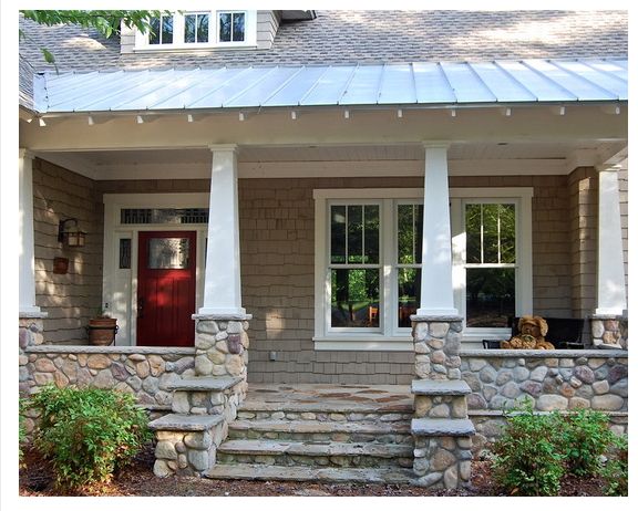 a dog is sitting on the front porch of a house with stone steps and pillars