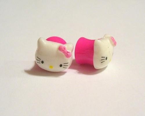 two hello kitty toys sitting next to each other on a white surface with pink trim