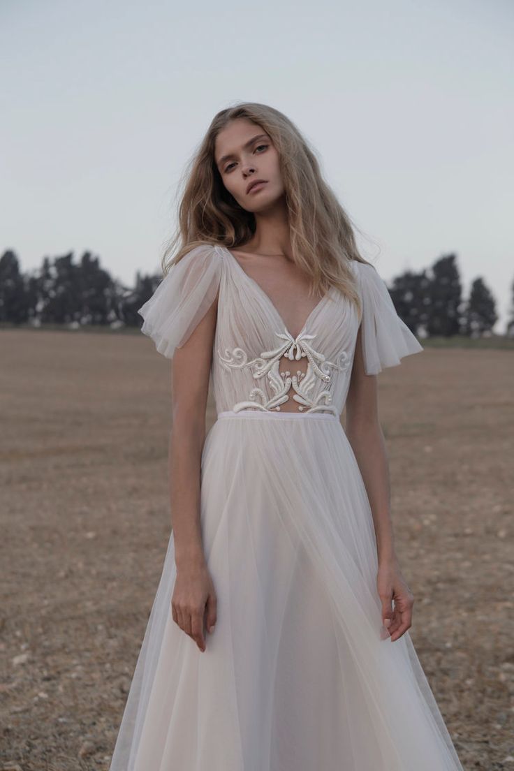 a woman standing in a field wearing a white dress