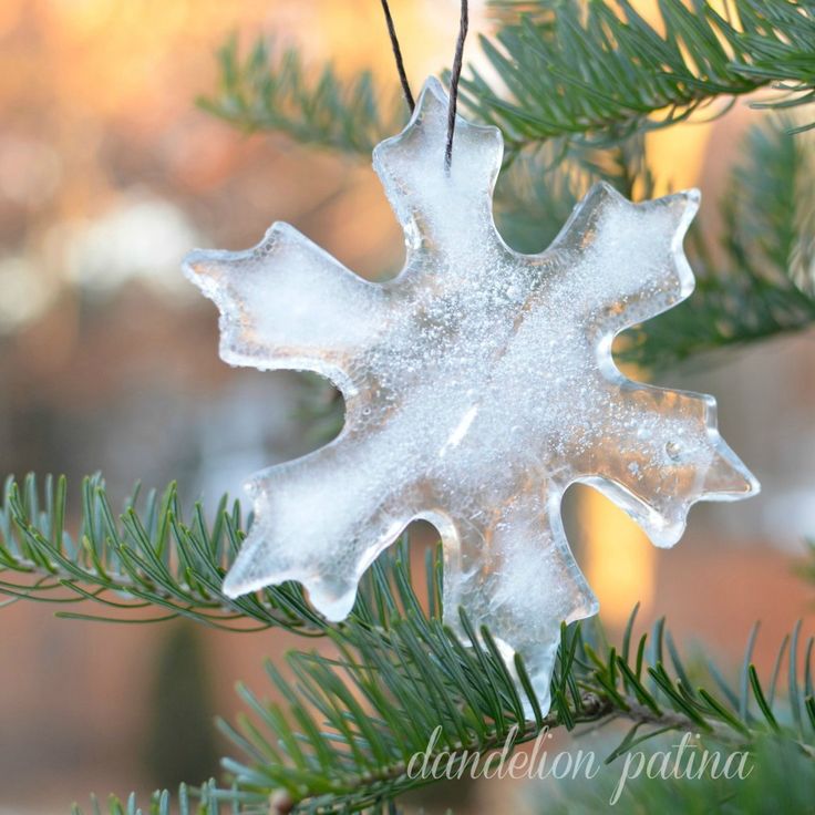 a snowflake ornament hanging from a pine tree