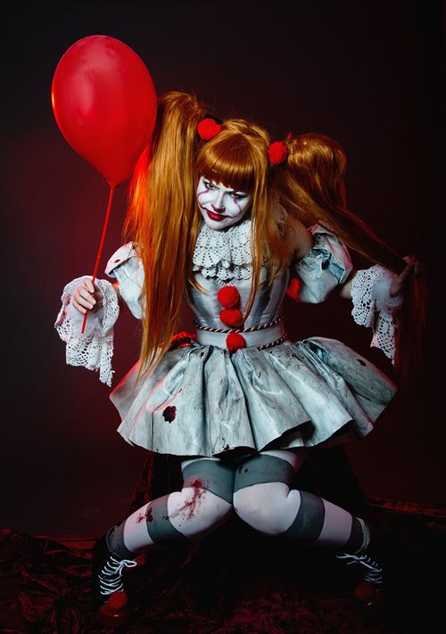 a woman dressed as a clown holding a red balloon