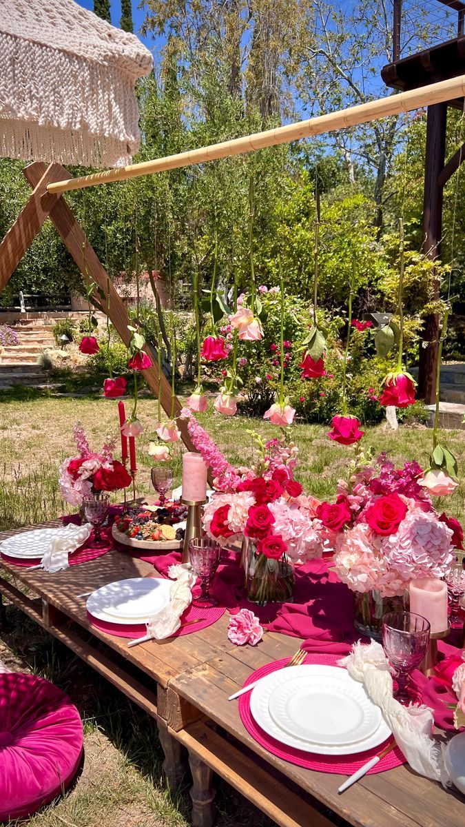 a table set up with pink flowers and plates for an outdoor dinner or bridal party