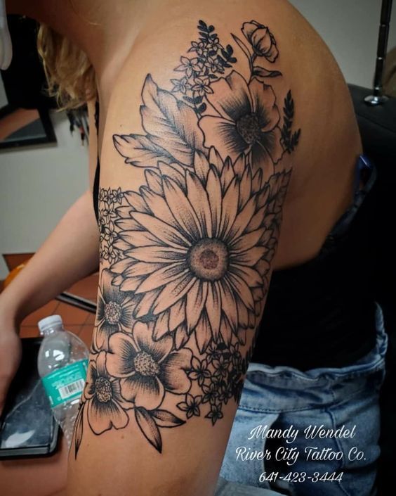 a woman's arm with black and white flowers on the back of her shoulder