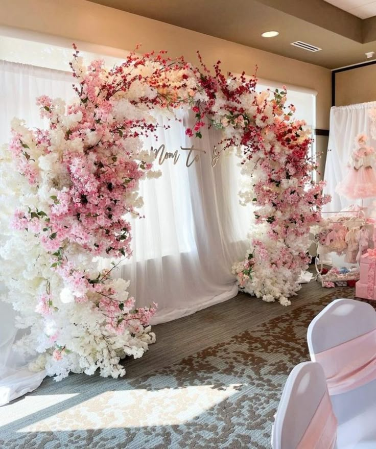 a wedding arch decorated with pink and white flowers for the entrance to the ceremony room