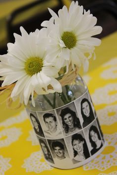 some white flowers are in a vase on a yellow tablecloth with pictures of people