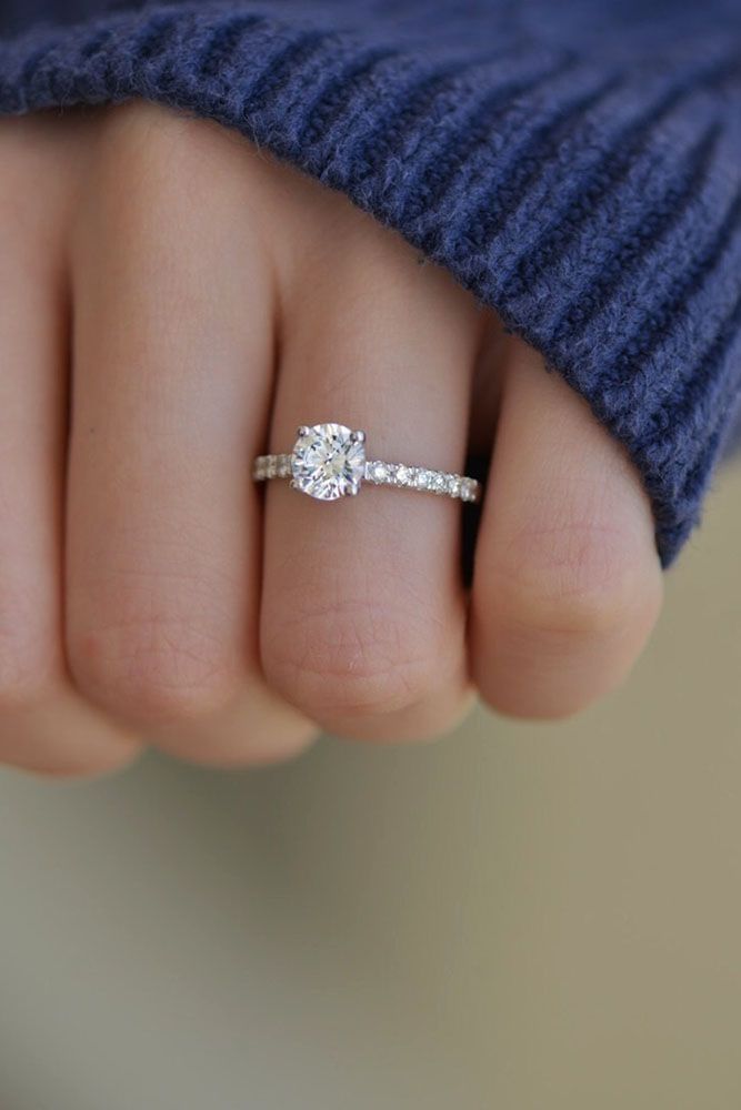 a woman's hand with a diamond ring on top of her finger, and the other hand holding an engagement ring