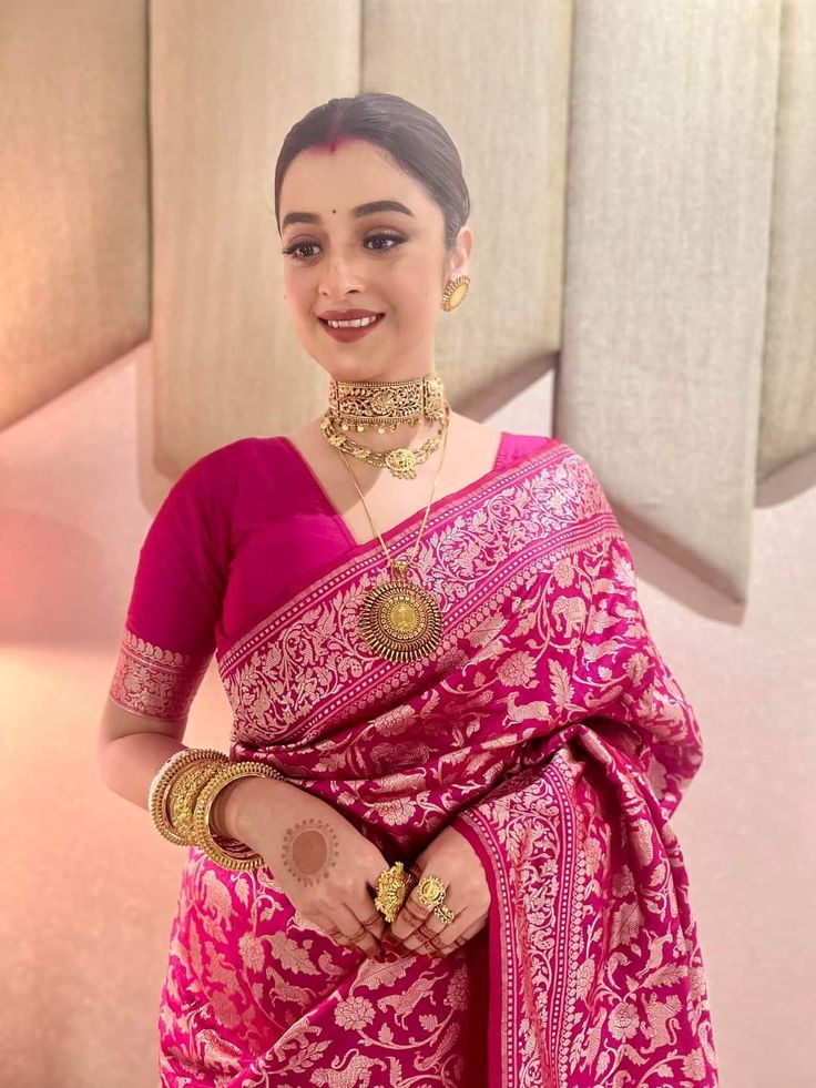 a woman wearing a pink sari and gold jewelry