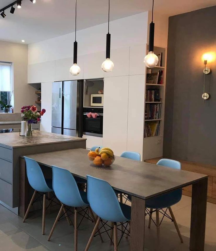 a kitchen table with blue chairs next to an island