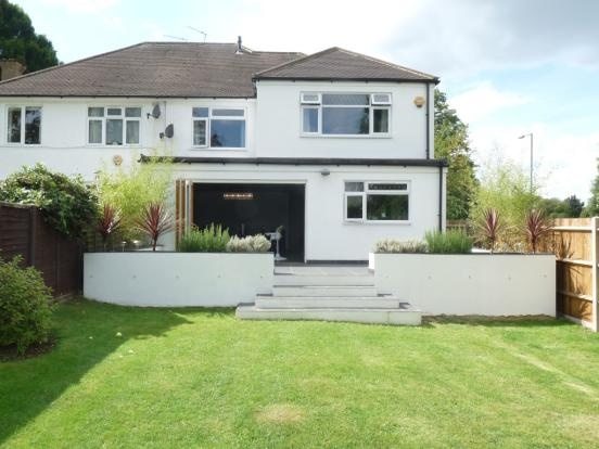 a large white house sitting on top of a lush green field next to a fence