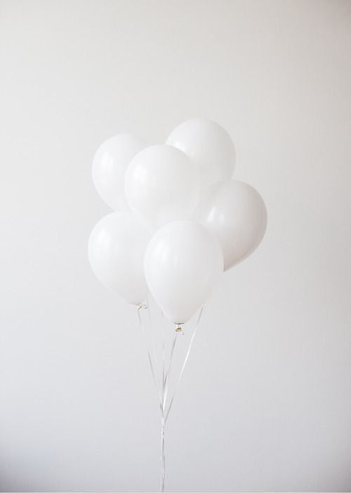 a bunch of white balloons floating on top of each other in front of a white wall