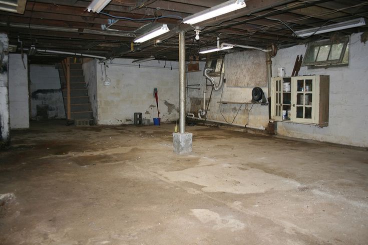 an empty room with exposed pipes and windows