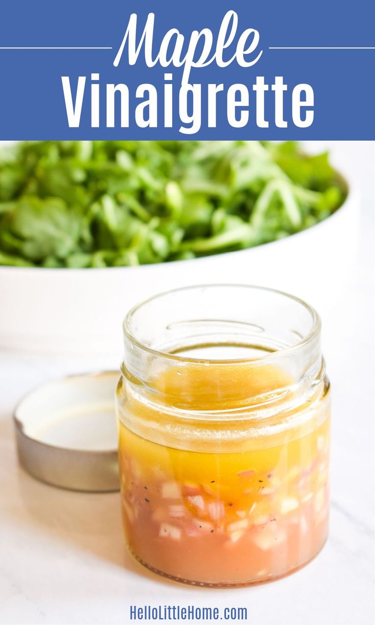 a glass jar filled with dressing next to a bowl of salad