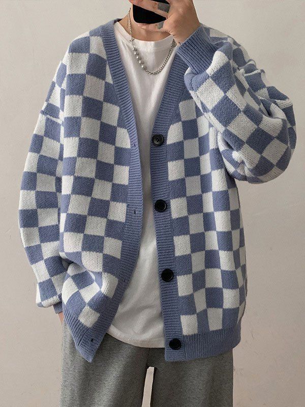 a man wearing a blue and white checkered cardigan sweater talking on a cell phone