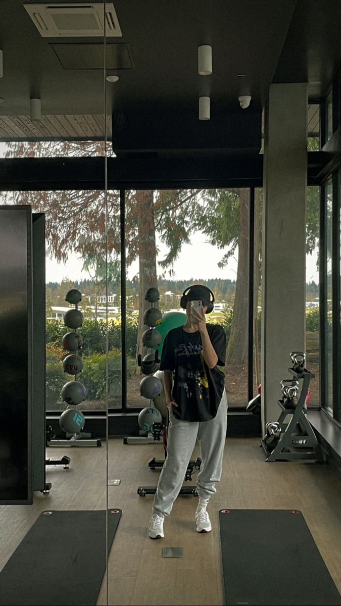 a man is standing in the middle of a gym with his headphones to his ears