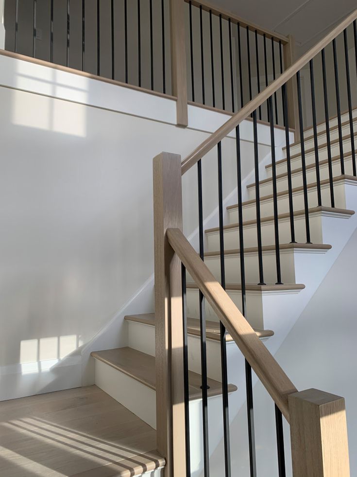 a white staircase with black railing and wooden handrail