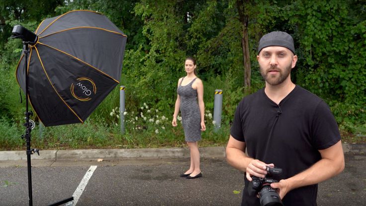 a man holding a camera in front of a woman with an umbrella on the street