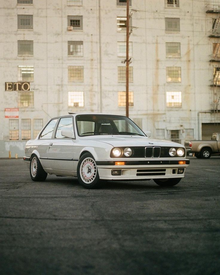 a white car parked in front of a tall building