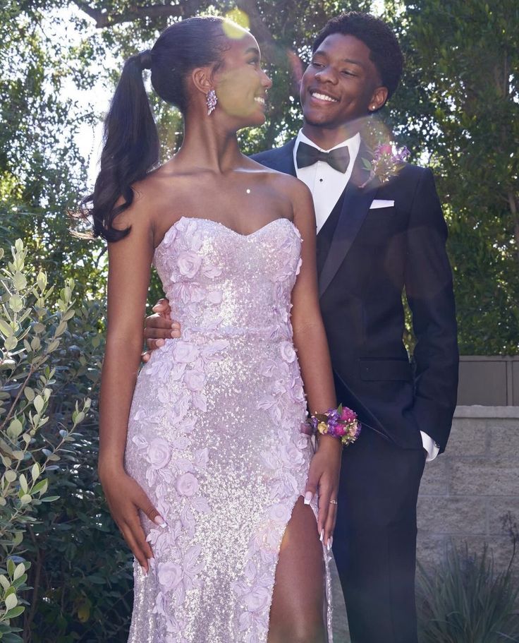 a man in a tuxedo standing next to a woman wearing a dress and tie