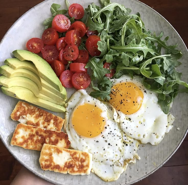 a plate with eggs, avocado, tomatoes and toasted bread on it