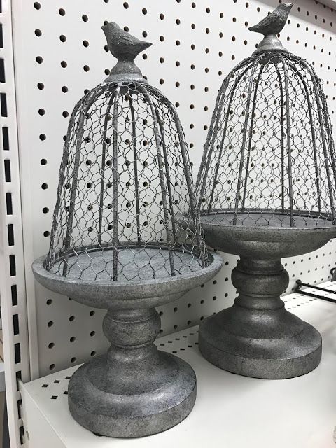 two birdcages sitting on top of a white shelf next to each other in a store