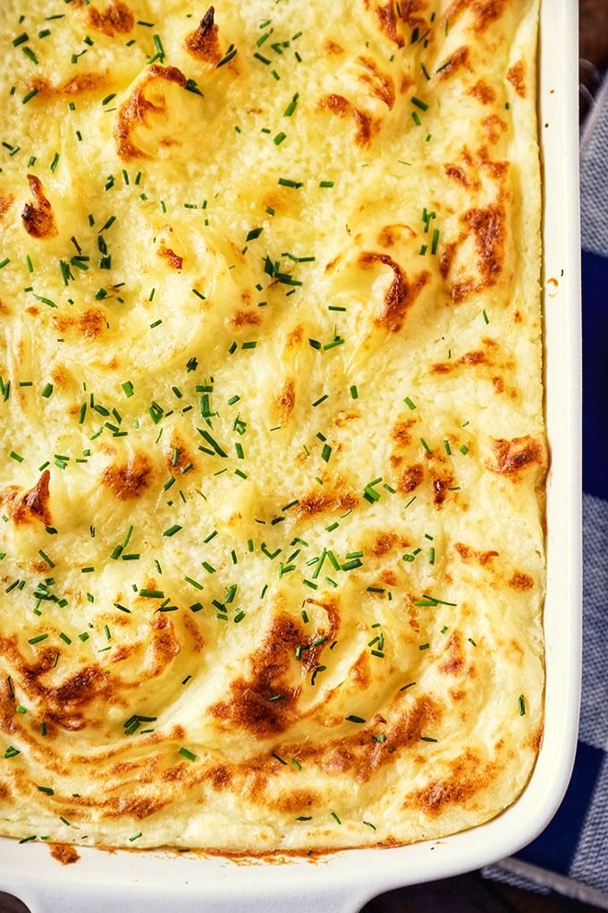 a casserole dish with cheese and herbs in it on a blue checkered table cloth