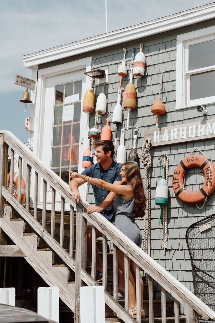 a man and woman standing on the steps of a boat house with life preservers