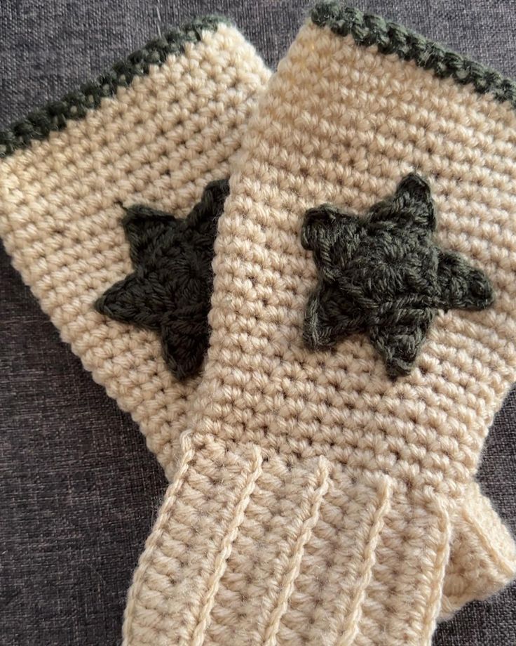 two crocheted mittens with black stars on them sitting on a gray surface