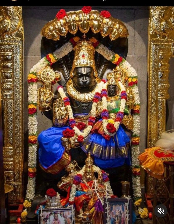 the statue is decorated with gold and red flowers on it's head, surrounded by other decorations