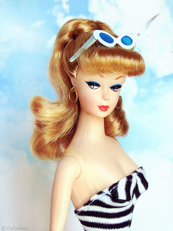 a barbie doll wearing sunglasses and a striped dress with her hair in a pony tail