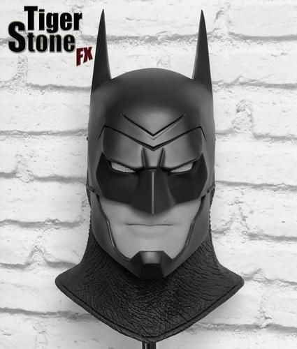 the batman mask is on display against a brick wall