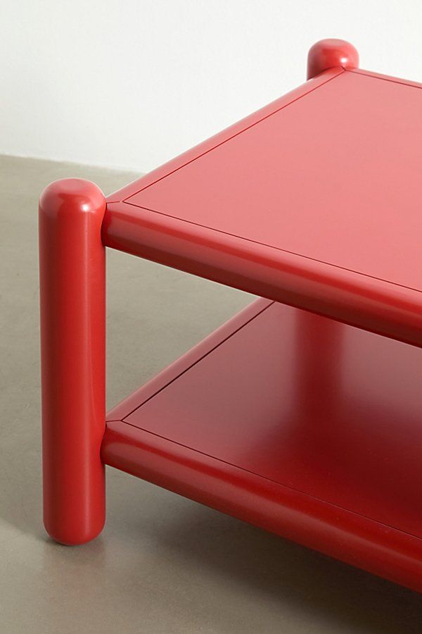 a red table sitting on top of a cement floor next to a white wall,