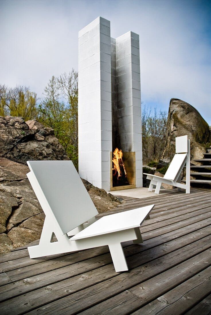 two white lawn chairs sitting on top of a wooden deck next to a fire place