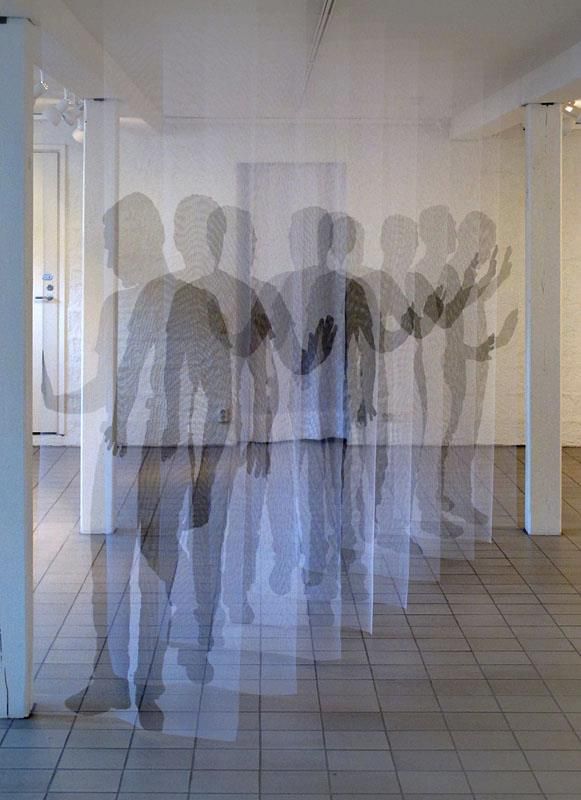 two people standing in an empty room with their shadows projected on the wall behind them