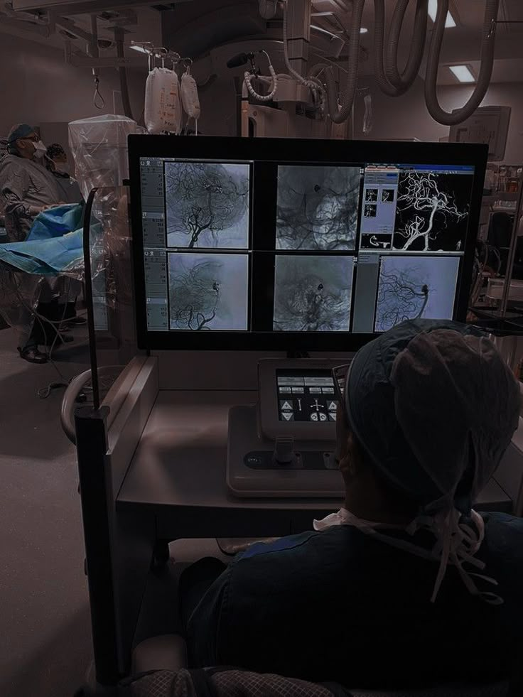 a person sitting at a desk in front of a computer with multiple screens on it