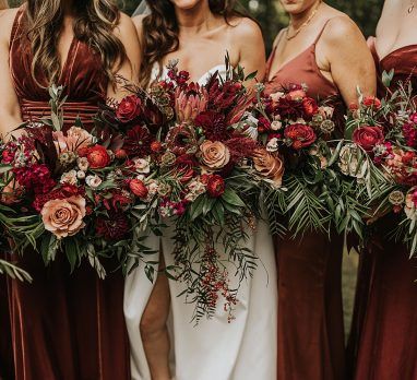 a group of women standing next to each other wearing dresses and holding bouquets in their hands