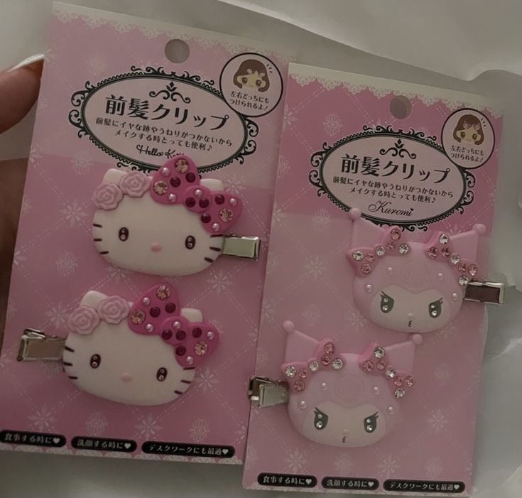 two hello kitty hair clips are shown in the package, one is pink and the other is white