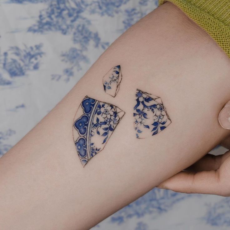 a woman's arm with two pieces of blue and white tattoos on it,