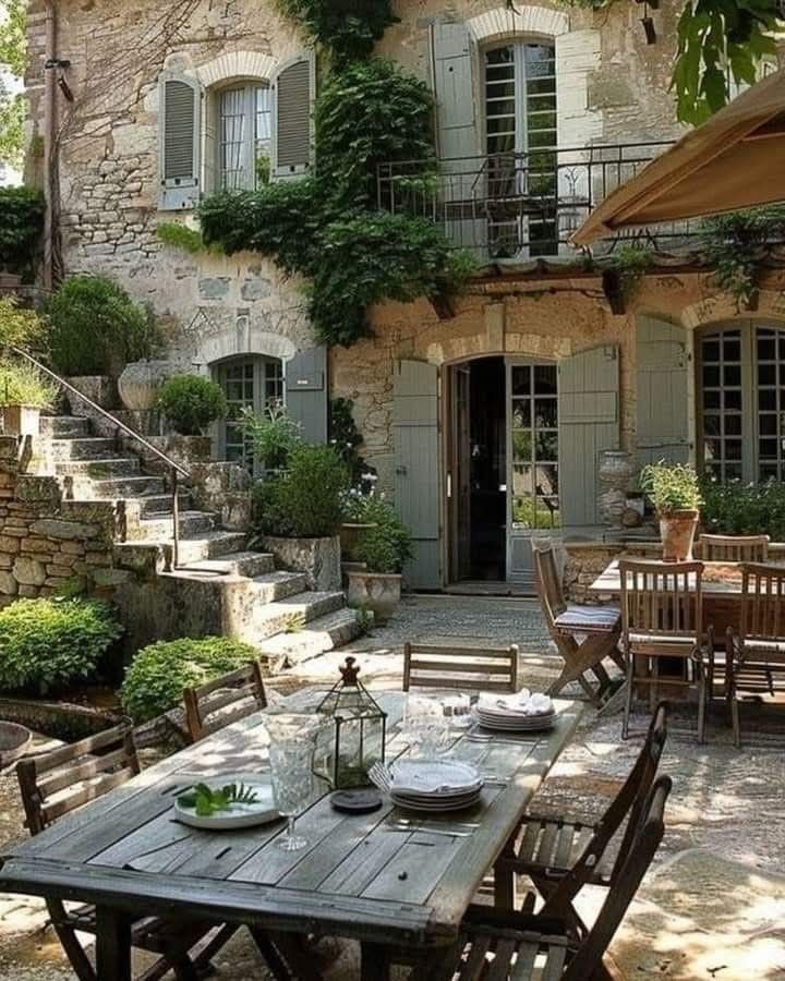 an outdoor dining area in front of a stone building with steps leading up to it