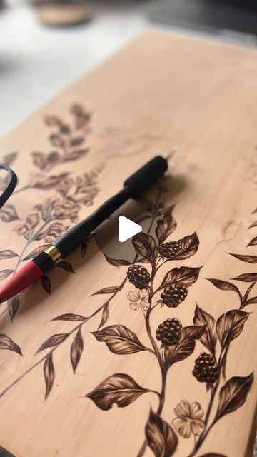 a wooden cutting board with flowers on it and a pair of glasses laying next to it