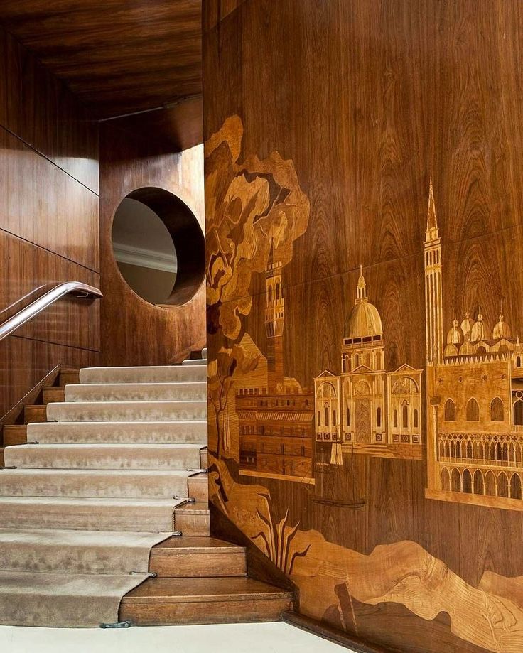 the stairs are painted with architectural drawings on wood paneling and handrails, along with a circular mirror