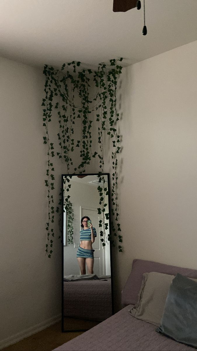 a bedroom with a bed, mirror and plant growing on the wall