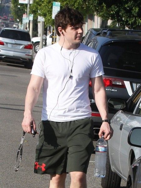 a man is walking down the street with his skateboard and water bottle in hand