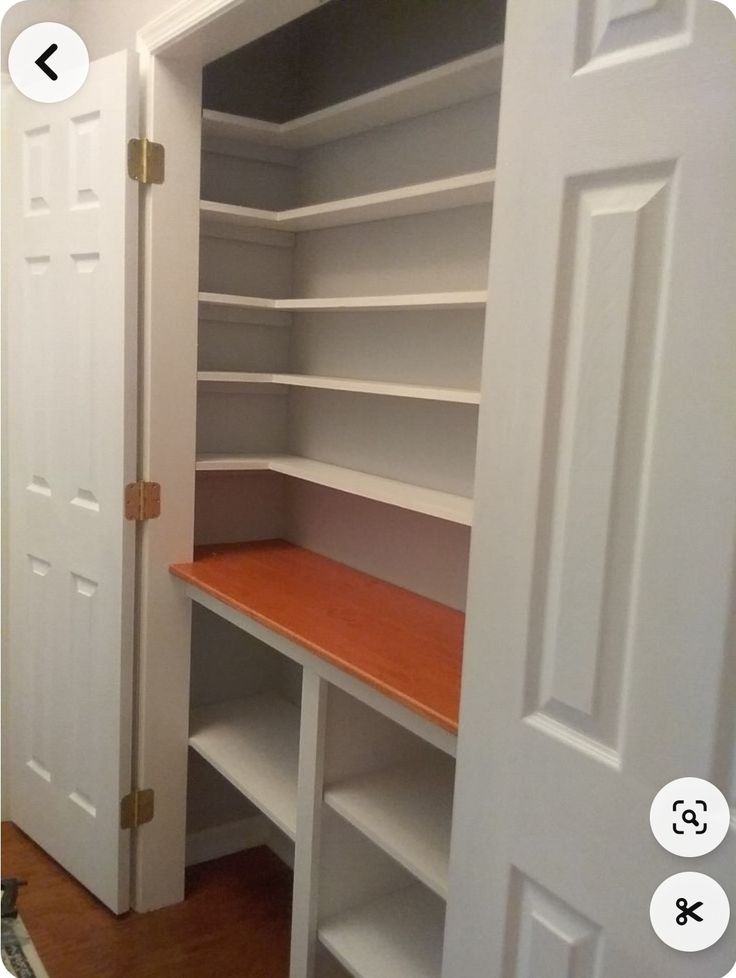 an empty closet with white shelves and wood flooring