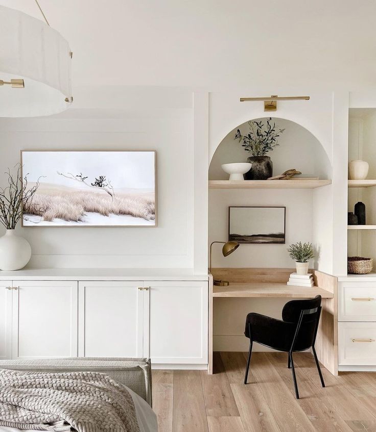 a bedroom with white walls and wooden flooring, built - in shelving units