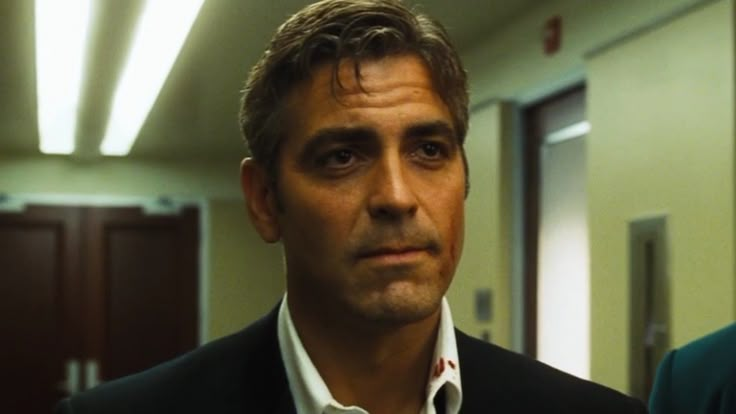 a man in a suit and tie looking at the camera while standing in an office hallway