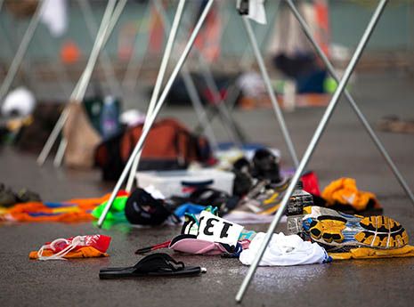 many pairs of shoes are sitting on the ground next to some poles and clothes hanging from them