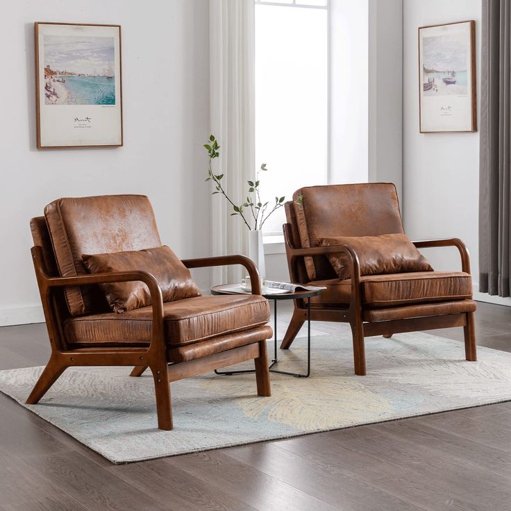 two brown leather chairs sitting on top of a rug in front of a white wall