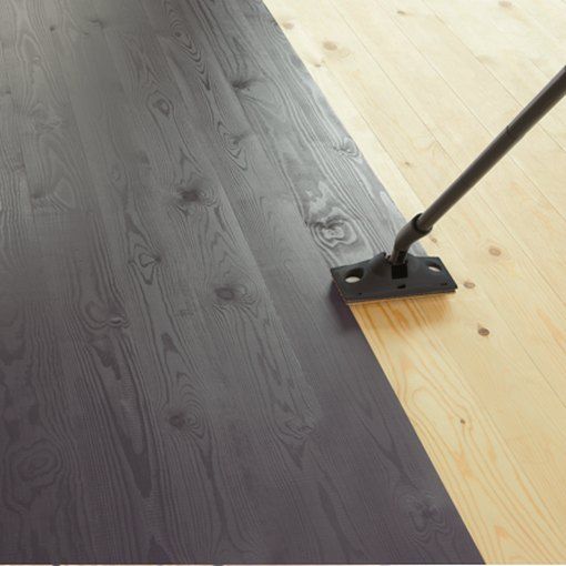 a person with a vacuum mop on top of a wooden floor next to a piece of wood