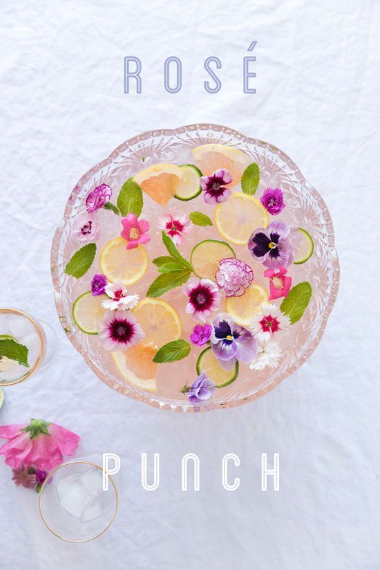 an overhead view of a glass dish with flowers and lemons in it on a white table cloth