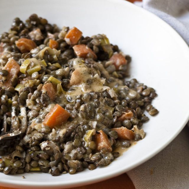 a white plate topped with lentils and carrots